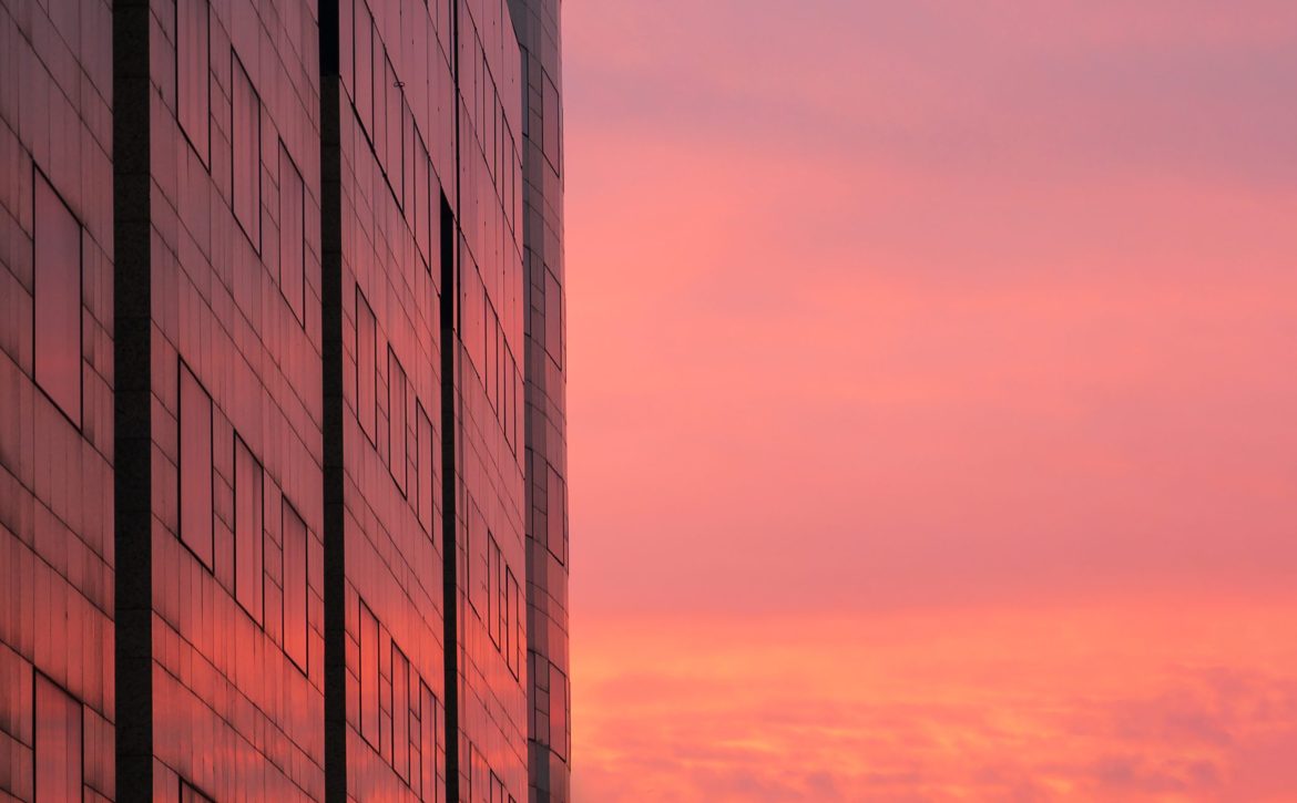 the colorful sky is reflected in the windows of the building
